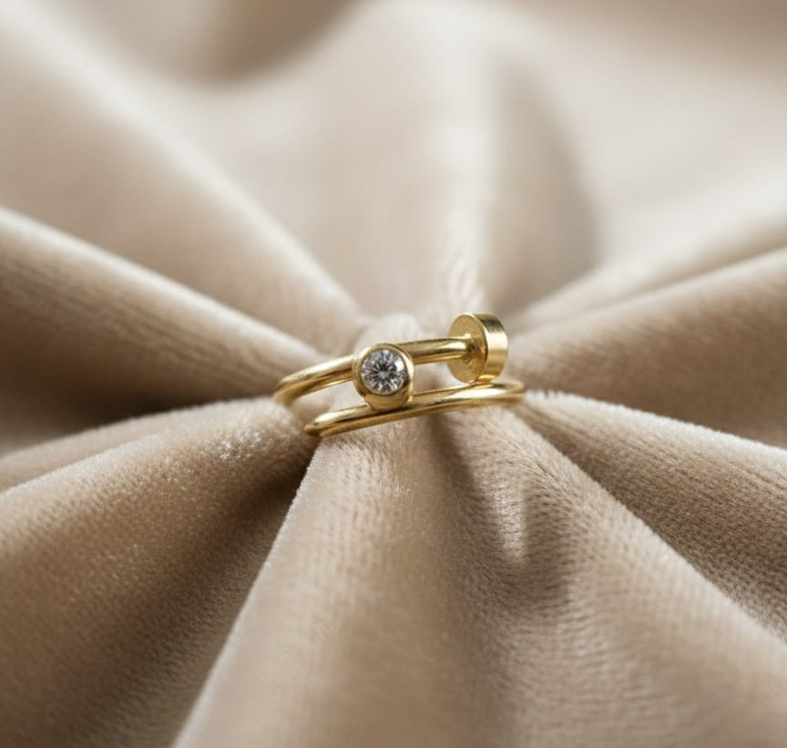 Gold ring with a diamond on a beige fabric background