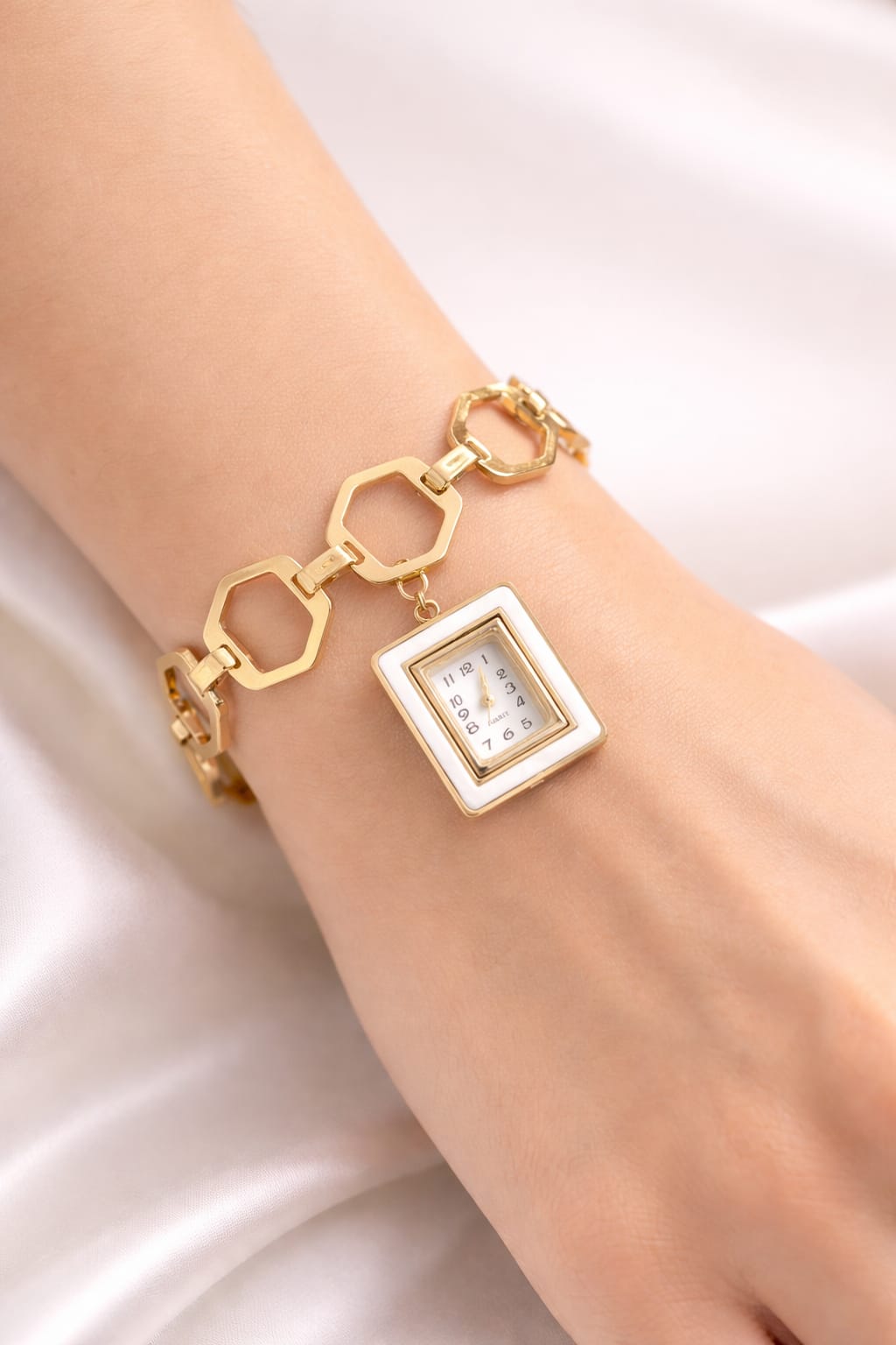 Gold bracelet with a square watch face on a white background
