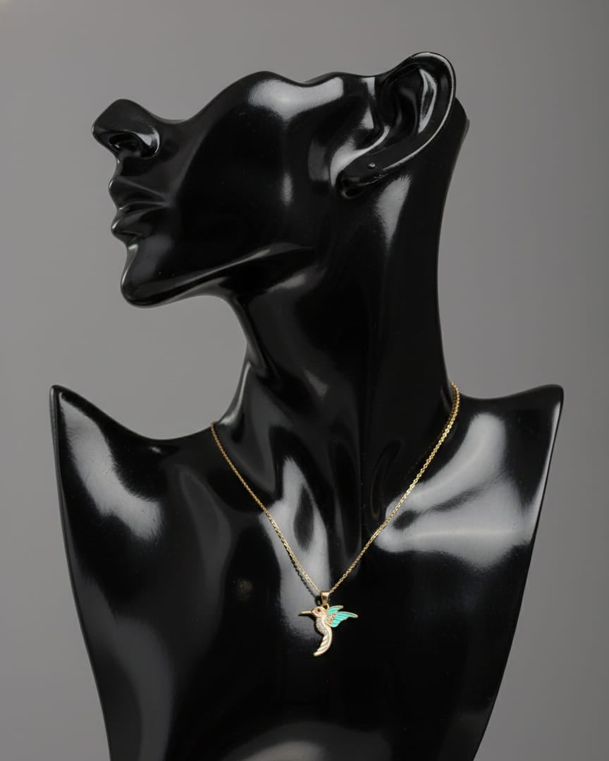 Black mannequin head with a gold necklace on a gray background