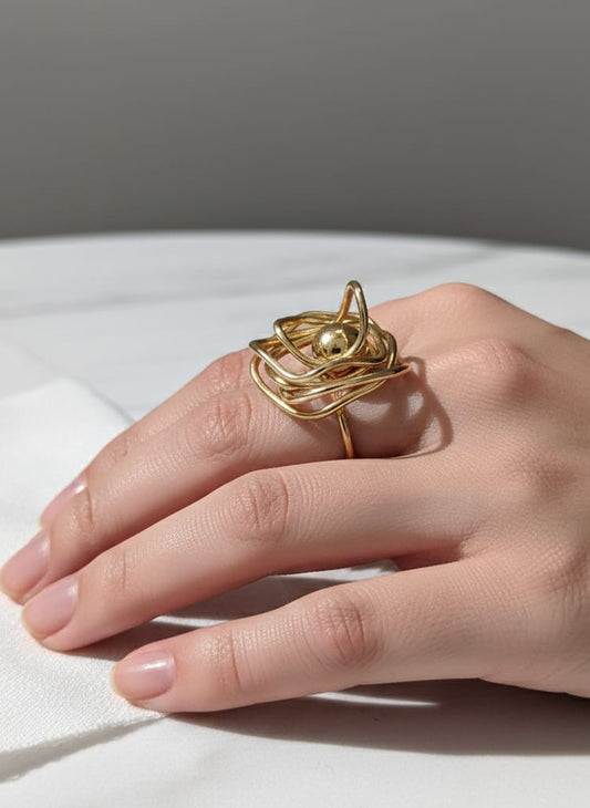 Gold ring on a hand against a neutral background
