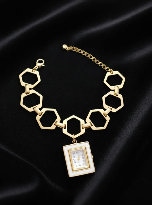 Gold hexagonal chain necklace with a rectangular pendant on a black satin background