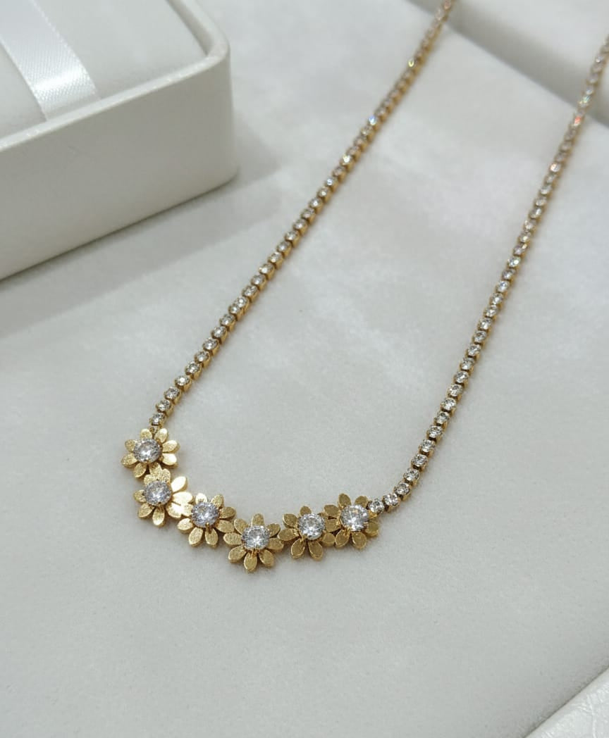 Gold necklace with floral design on a white surface